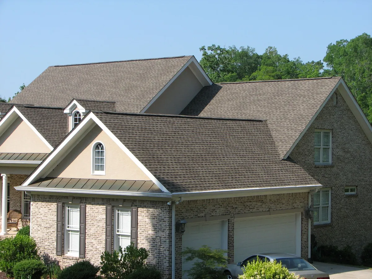 Brick and stone home after a brown architectural shingle roof replacement