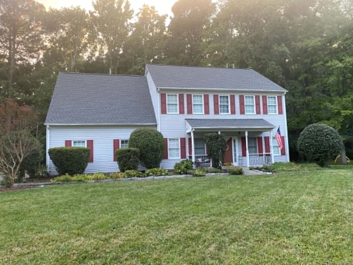 Two-story colonial home with red shutters after a gray architectural shingle roof replacement