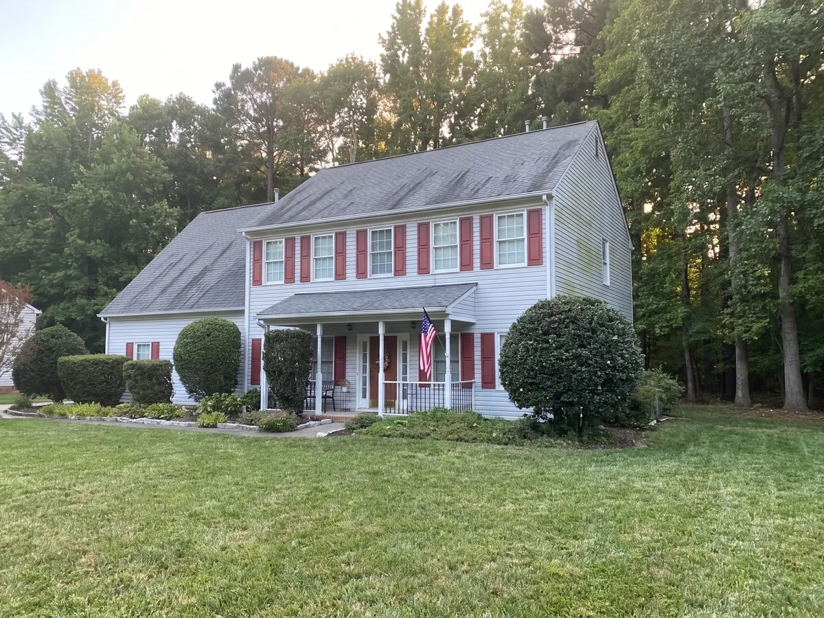 The same colonial home before the roof replacement, with a faded and worn shingle roof