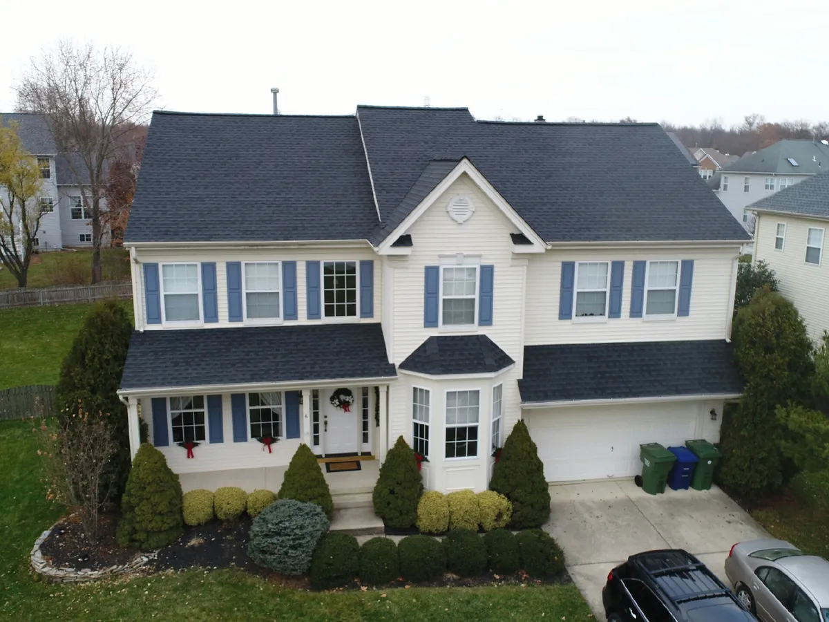 Drone view of a two-story home after a charcoal shingle roof replacement